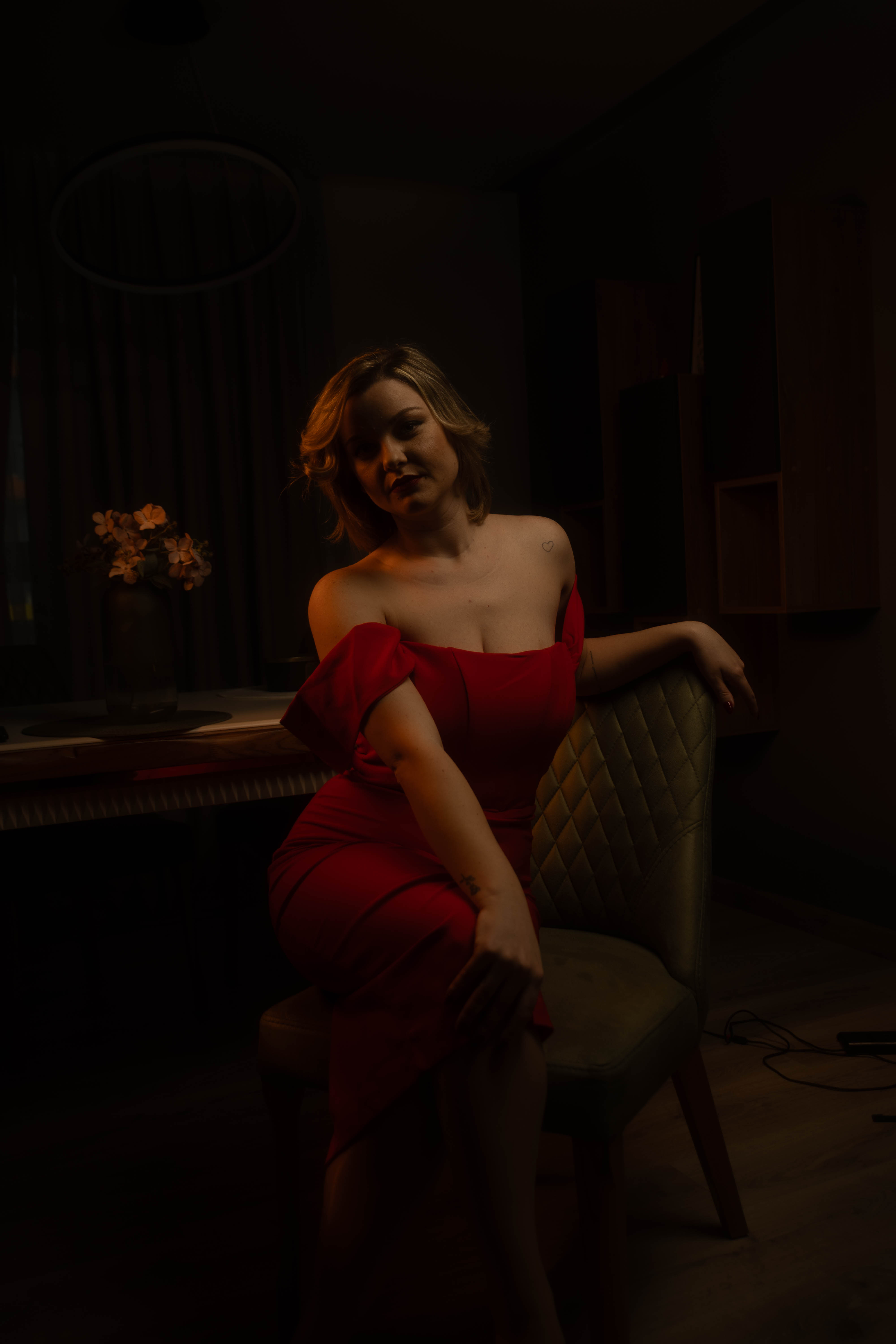 Editorial red dress, green velvet chair, moody low-key interior