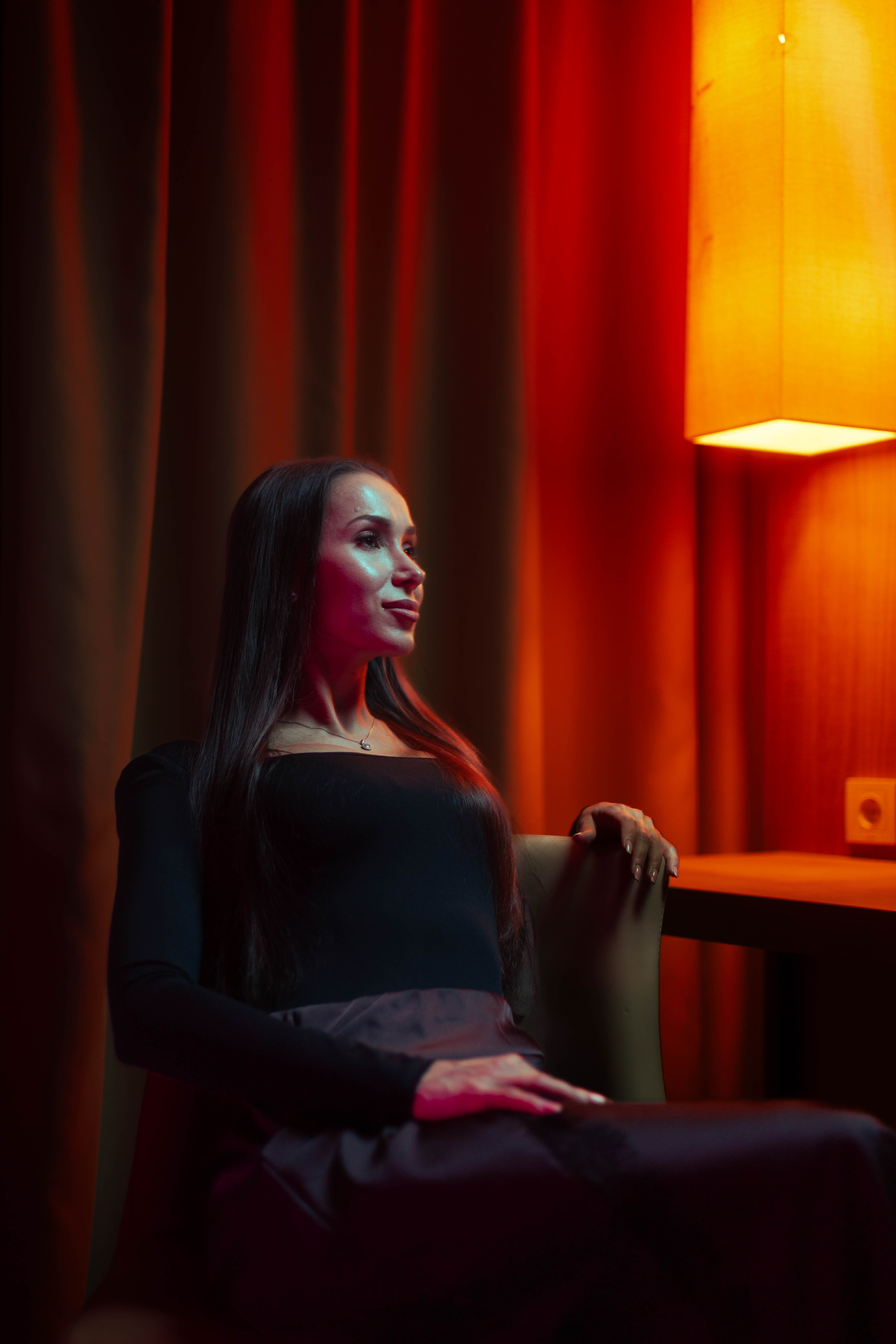 Brand campaign, full-length seated regal pose, ember curtain backdrop
