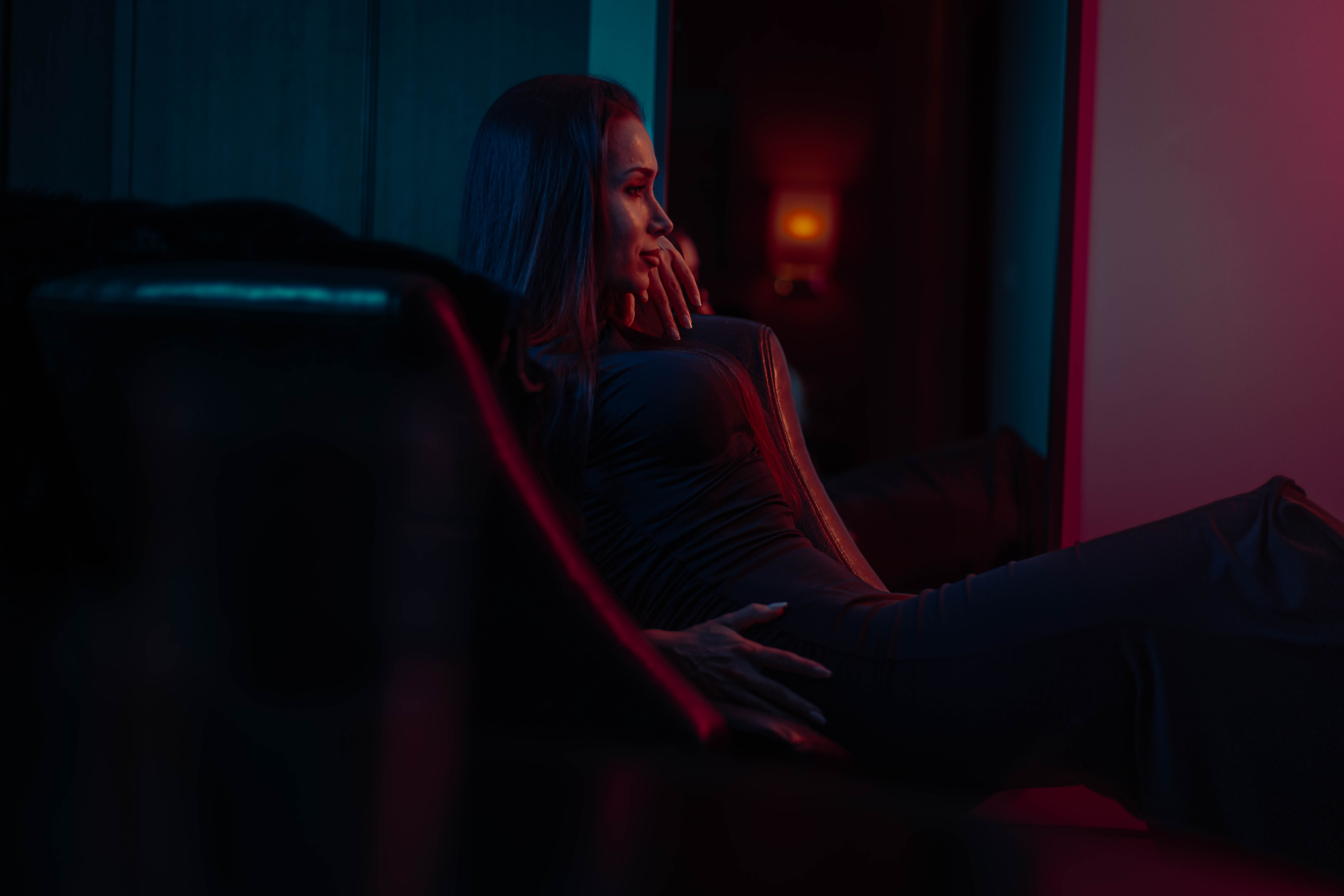 Editorial colour split, teal and crimson on lounge, reclining pose