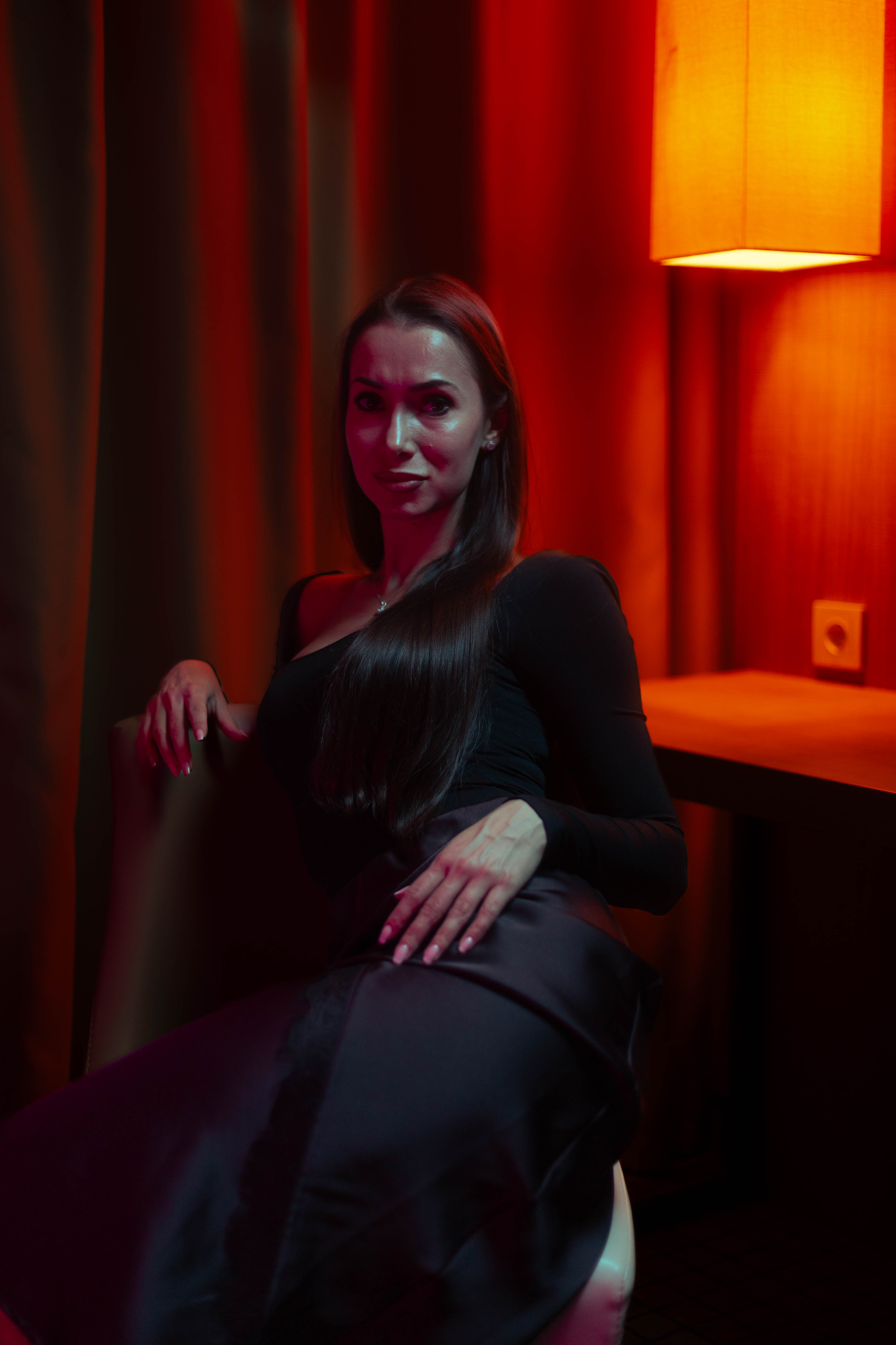 Editorial seated portrait, ember and crimson palette, sculpted shadow