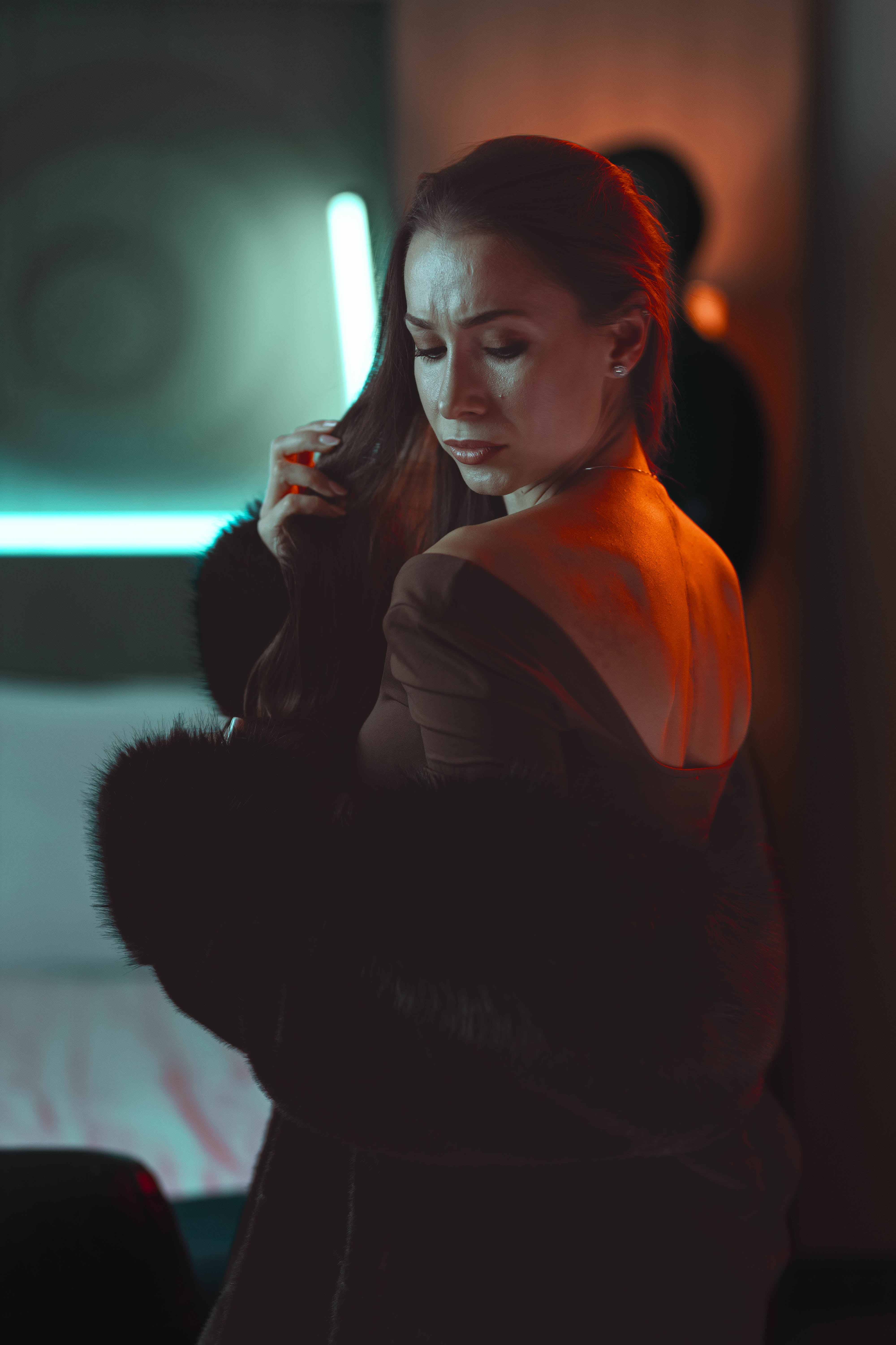 Fashion film still, pensive downward gaze, neon backlight